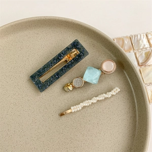 Detailed set of elegant pearl and geometric hair clips on a ceramic jewelry tray