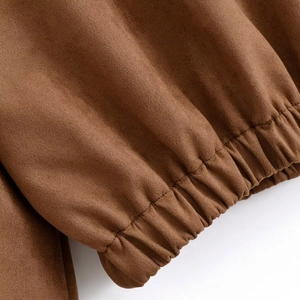 Detailed close-up of brown suede jacket showing elastic cuffs and premium fabric texture