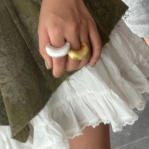Detailopname van gouden en zilveren chunky ringen gedragen op hand over groene stof