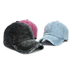 Detailed view of three distressed washed cotton baseball caps in black, pink, and light blue
