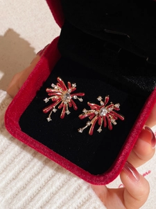 Detail of red fireworks stud earrings with gold accents and rhinestones in a gift box