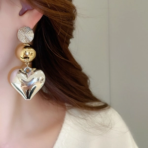 Detailed view of silver textured stud with gold bead and large heart-shaped drop earrings