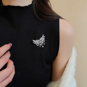 Detail of silver pearl brooch with zircons worn on a black sleeveless top for women