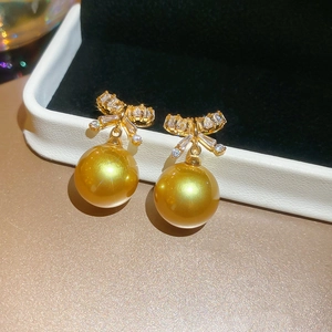 Macro view of champagne pearl earrings with sparkling bowknot zircon details in a jewelry box