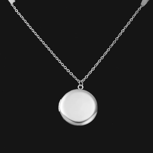 Détail du collier médaillon rond en acier inoxydable 316L argent poli sur fond noir
