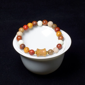 Detailed close-up of mixed wood Buddhist beads with carved central barrel bead and gold spacers