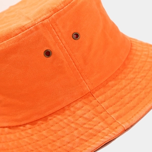 Détail d'un bob en coton orange fluo montrant les œillets en métal et le sergé