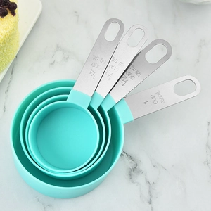 4-piece stainless steel and teal measuring cup set for baking on marble background