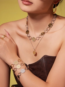 Close-up of gold and silver layered necklaces with embossed circular pendants and zircon