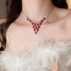 Detail of V-shaped silver necklace with red crystals and diamond tassel on model