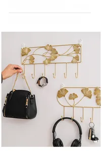 Detail view of golden ginkgo leaf wall hooks with bag and keys on grey background