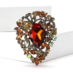 Detail of vintage heart brooch with red teardrop gemstone and amber rhinestones