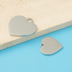 Close-up of polished silver heart pendants on a textured beige stone background