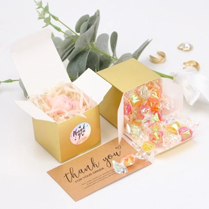 Detail of gold cube gift box with open lid, internal filling, thank you cards and stickers