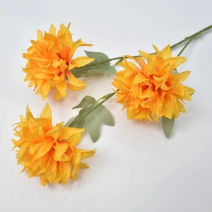 Detail of three-headed artificial yellow pompon mum flower with green leaves for decor