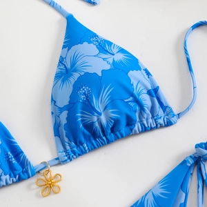 Close-up of blue hibiscus floral bikini top with a decorative golden flower pendant