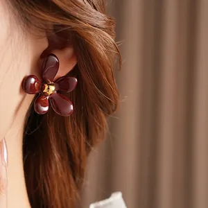 Retro burgundy flower stud earrings with a gold center bead and polished finish
