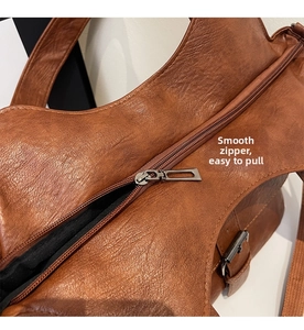 Close-up of the smooth dark metal zipper and textured brown leather on the tote bag