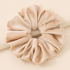 Close-up of champagne velvet scrunchie showing detailed soft pleated texture and sheen