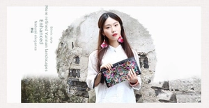 Close-up of black ethnic embroidery clutch featuring vibrant floral patterns and pink tassels