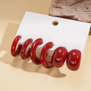 Detailed view of six-piece dark red acrylic drop earrings on white jewelry card with stone