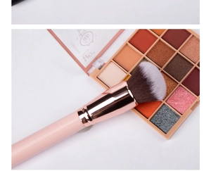 Detailed shot of dense synthetic foundation brush resting on a 16-color eyeshadow palette