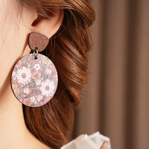 Close-up of vintage round wooden earrings with floral patterns worn by a model