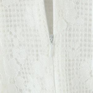 Robe courte en dentelle blanche avec détails boutonnés et gros plan sur la fermeture