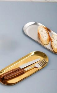 Macro view of oval gold and silver stainless steel trays with wooden handle cutlery