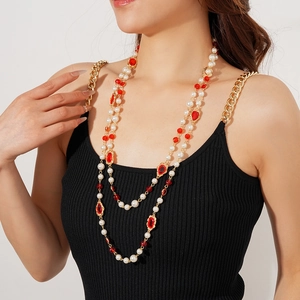 Close-up of vintage multi-layer pearl necklace with red gemstones and gold chain on model