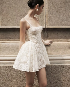 Détail de la robe courte en dentelle blanche avec motif floral et jupe bouffante évasée