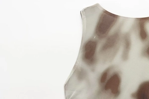 Makro-Detail des gerafften Netz-Kleides mit braunem Batik-Muster am Ausschnitt auf Creme