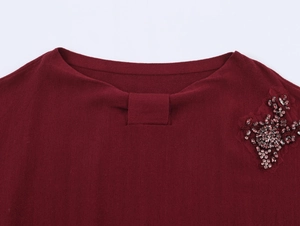 Close-up of wine red knit top neckline with handmade beaded flower and knotted detail