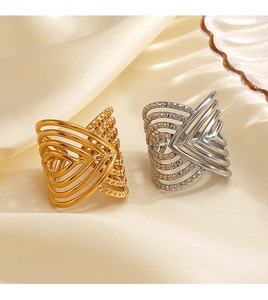 Macro detail of 18K gold and silver chunky crisscross rings on beige silk fabric
