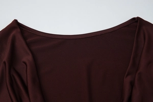 Dettaglio dello scollo a V e della trama in maglia a coste sul vestito bordeaux scuro
