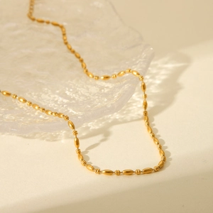 Minimalist 18K gold plated stainless steel oval bead necklace on glass base