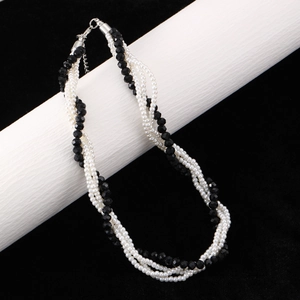 Détail d'un collier multirangs torsadé avec perles d'onyx noires et perles nacrées