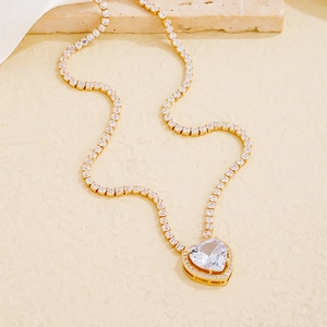 Macro shot of gold tennis chain with sparkling heart pendant on elegant display