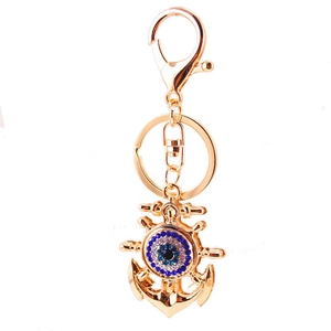 Golden ship anchor keychain with evil eye charm and rhinestones on a white background