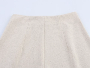 Detailed macro view of the linen fabric texture and waist stitching on beige trousers