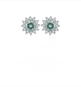 Detailed view of silver snowflake stud earrings featuring centered green moissanite stones