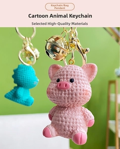 Detail of pink pig and cyan creature resin keychains with woven texture and gold bell