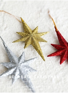 Macro detail of glittery gold, silver, and red star ornaments for Christmas tree decoration