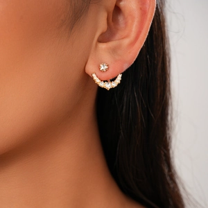Detail of elegant gold star-shaped stud earring with curved zircon pavé on model's ear