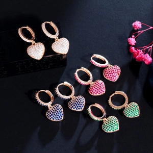 Gros plan sur des boucles d'oreilles cœur avec zircons colorés et plaqué or