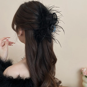 Detail view of large black feather hair claw with lace mesh on model's hair