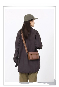 Dettaglio borsa a tracolla vintage in pelle marrone mostrata su modella in posa