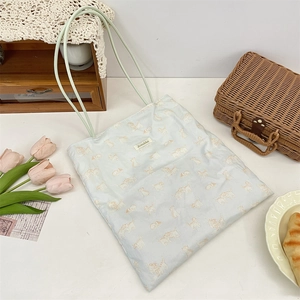 Detail of light blue canvas tote bag featuring cute cat prints and a Szakka woven label