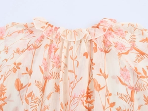 Detailansicht des Rüschenrundhalsausschnitts am Chiffonkleid mit rosa Blumenmustern