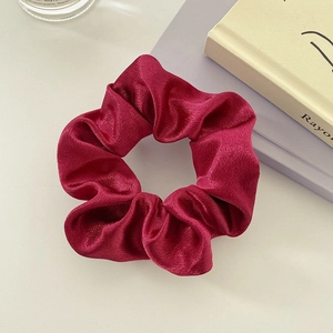 Detail showing smooth satin texture and elegant pleats of the burgundy scrunchie